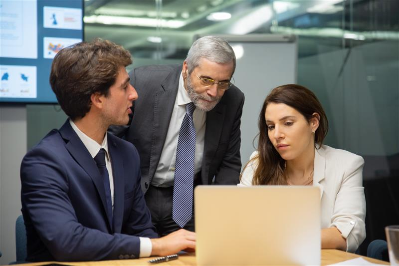 a group of people looking at a laptop